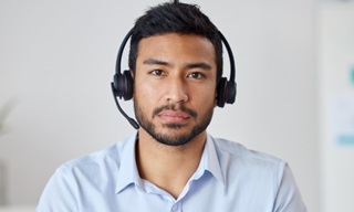 Rapaz com headphones de contact centre a olhar de frente para o leitor